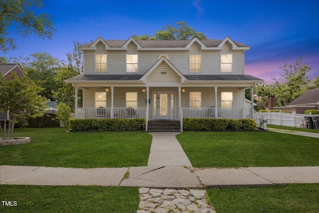 view of front of home featuring a porch, a lawn, roof with shingles, and fence