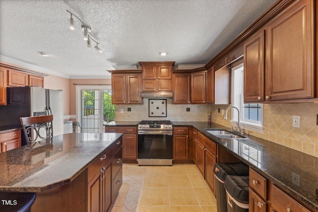 kitchen with brown cabinets, a sink, light tile patterned floors, ornamental molding, and stainless steel appliances