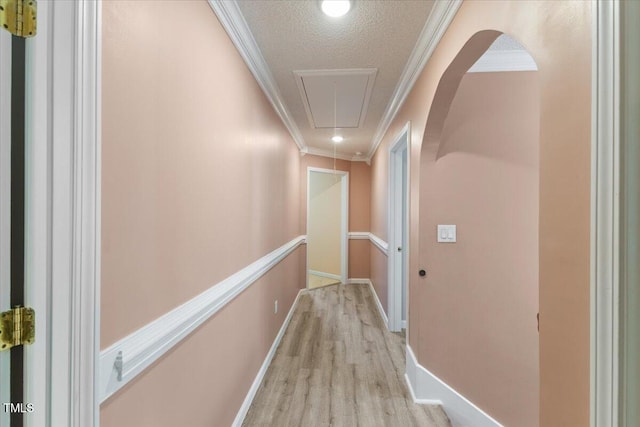 hall with attic access, a textured ceiling, crown molding, wood finished floors, and an upstairs landing
