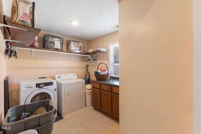laundry room with a textured ceiling, cabinet space, independent washer and dryer, and visible vents