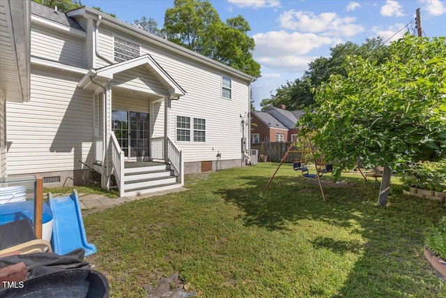 rear view of house with fence and a yard