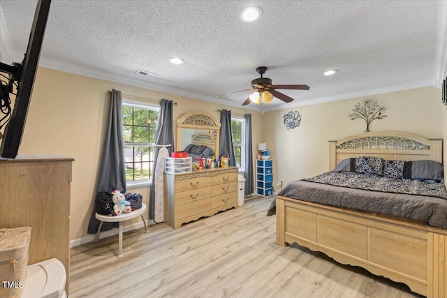 bedroom with ornamental molding, light wood finished floors, a textured ceiling, and visible vents
