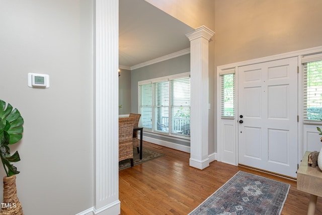 entrance foyer featuring crown molding, baseboards, decorative columns, and wood finished floors