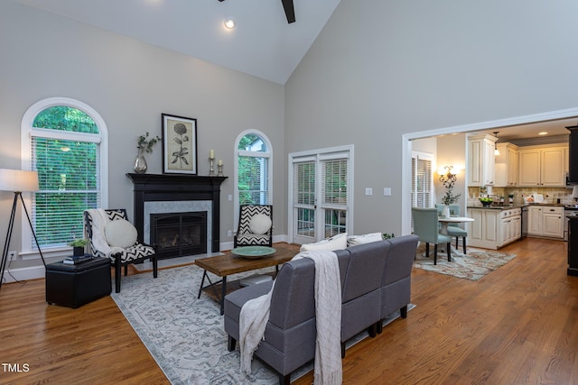 living area featuring a ceiling fan, a high end fireplace, wood finished floors, high vaulted ceiling, and recessed lighting