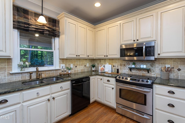 kitchen with backsplash, pendant lighting, appliances with stainless steel finishes, light wood-type flooring, and a sink