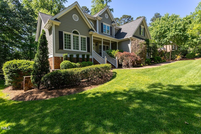 exterior space featuring a lawn, roof with shingles, and brick siding