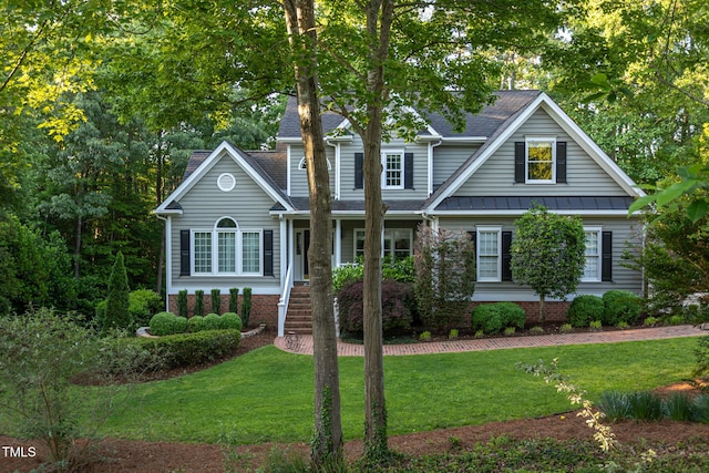 view of front of house with a standing seam roof, a shingled roof, and a front yard