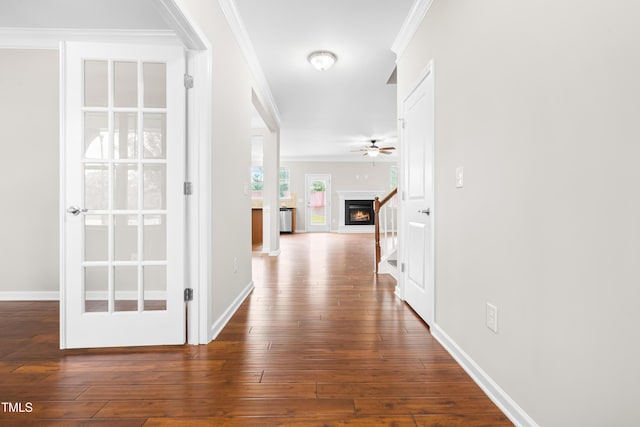 hall featuring crown molding, baseboards, and hardwood / wood-style floors
