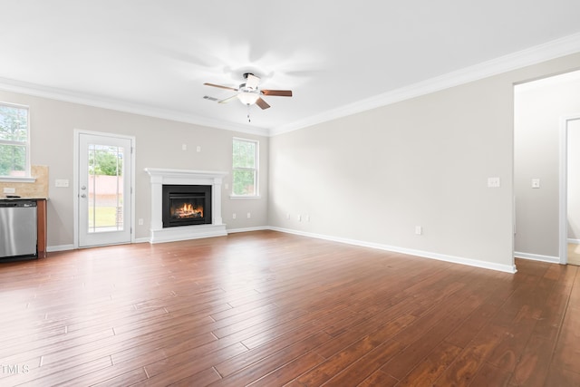 unfurnished living room with a ceiling fan, a glass covered fireplace, a wealth of natural light, and wood finished floors