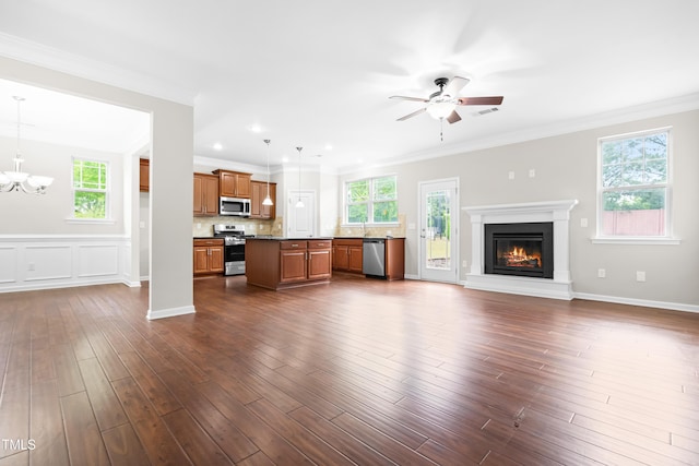unfurnished living room featuring a glass covered fireplace, ceiling fan with notable chandelier, dark wood finished floors, and a healthy amount of sunlight