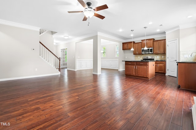 kitchen featuring crown molding, dark countertops, brown cabinets, open floor plan, and stainless steel appliances