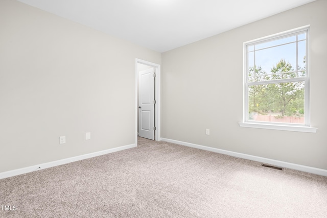 carpeted empty room with baseboards, a healthy amount of sunlight, and visible vents