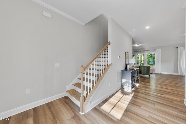 stairway with visible vents, wood finished floors, baseboards, ornamental molding, and recessed lighting