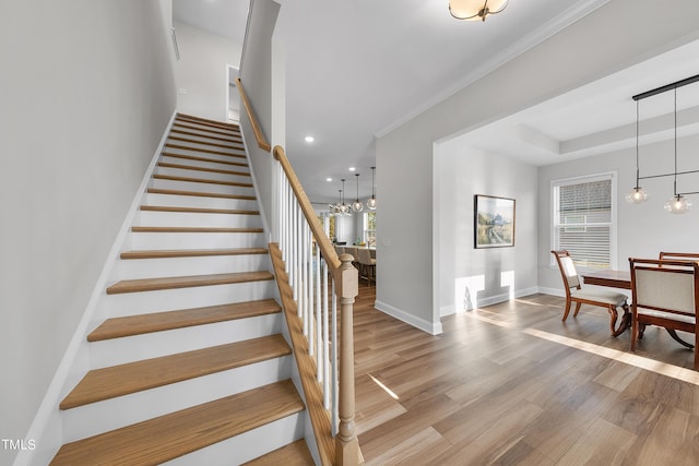 stairway featuring crown molding, wood finished floors, baseboards, recessed lighting, and a notable chandelier