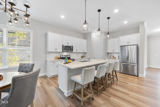 kitchen with appliances with stainless steel finishes, tasteful backsplash, a sink, light countertops, and white cabinetry