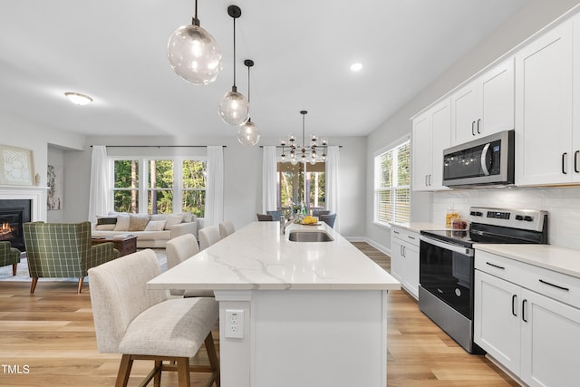 kitchen with a sink, light wood-style floors, a kitchen breakfast bar, stainless steel appliances, and open floor plan