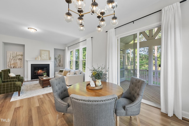 dining area featuring a chandelier, a glass covered fireplace, and light wood finished floors