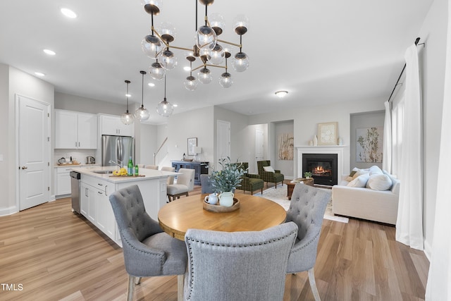 dining room with recessed lighting, baseboards, a glass covered fireplace, and light wood-type flooring