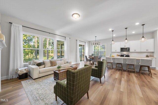 living area featuring recessed lighting, light wood finished floors, baseboards, and a notable chandelier