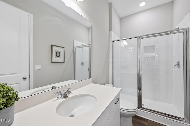 bathroom featuring vanity, wood finished floors, toilet, and a shower stall