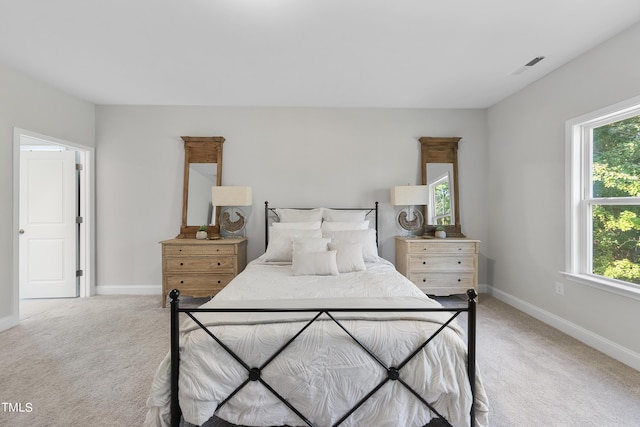bedroom featuring baseboards, light colored carpet, and visible vents
