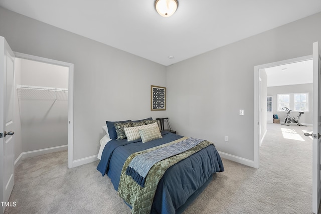 carpeted bedroom with baseboards, a walk in closet, and a closet