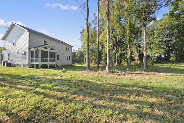 view of yard with central air condition unit and a sunroom