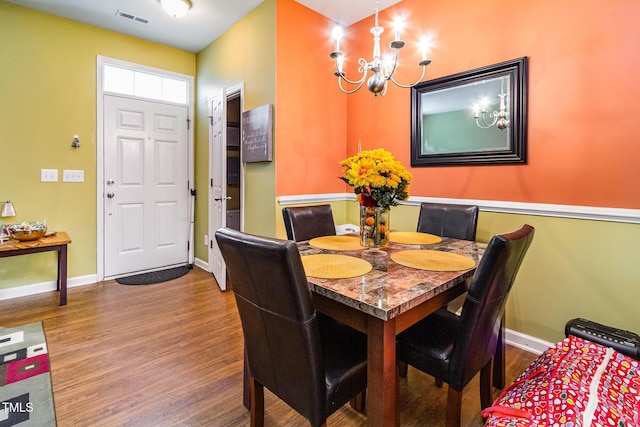 dining room with a chandelier, wood finished floors, and baseboards