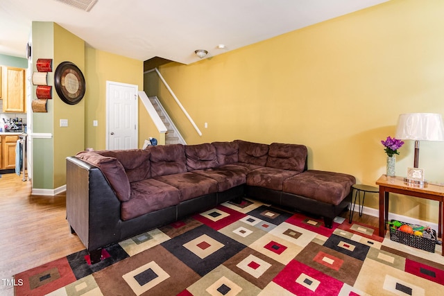living room featuring wood finished floors, stairs, and baseboards