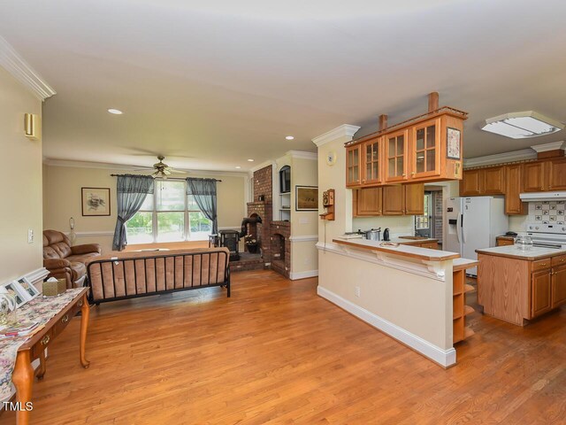 2371 NC-210, Smithfield, NC 27577 - kitchen with open floor plan, under cabinet range hood, crown molding, a peninsula, and brown cabinetry