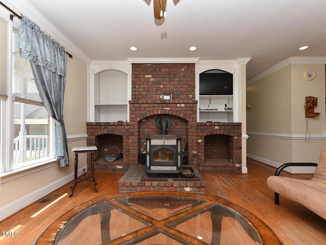 2371 NC-210, Smithfield, NC 27577 - living room with wood finished floors, baseboards, a wood stove, crown molding, and ceiling fan