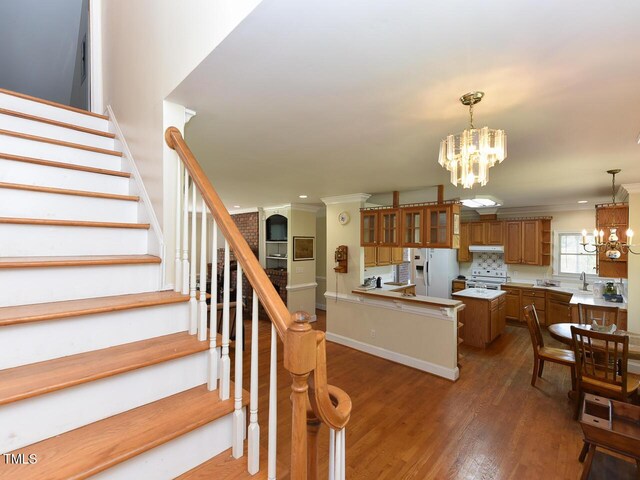 2371 NC-210, Smithfield, NC 27577 - kitchen featuring white appliances, a chandelier, brown cabinets, ornamental molding, and under cabinet range hood