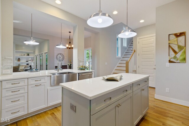 211 Page St, Morrisville, NC 27560 - kitchen featuring stainless steel dishwasher, a kitchen island, light countertops, a sink, and light wood finished floors
