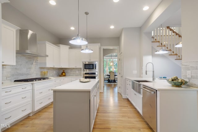 211 Page St, Morrisville, NC 27560 - kitchen with a sink, appliances with stainless steel finishes, light wood-style flooring, and wall chimney exhaust hood