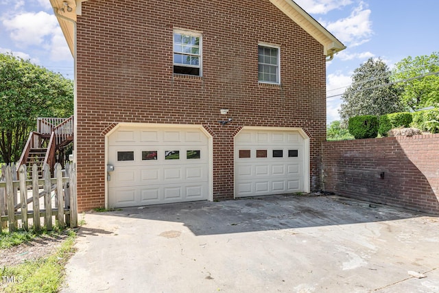 garage featuring fence and driveway