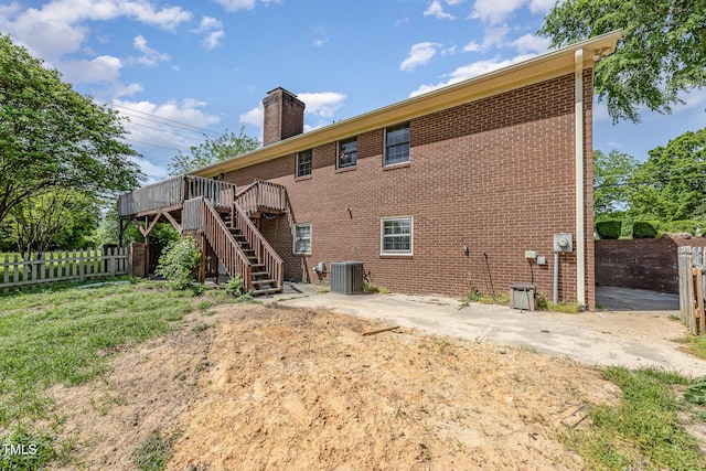 rear view of property featuring a chimney, a deck, cooling unit, a fenced backyard, and stairs