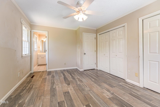 unfurnished bedroom with baseboards, ornamental molding, a closet, and hardwood / wood-style floors