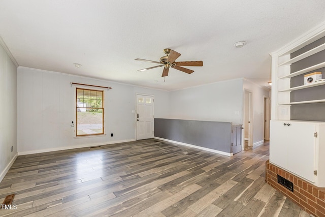 empty room with baseboards, ceiling fan, ornamental molding, and wood finished floors