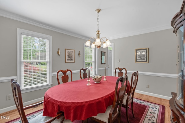 dining space with a chandelier, wood finished floors, crown molding, and baseboards
