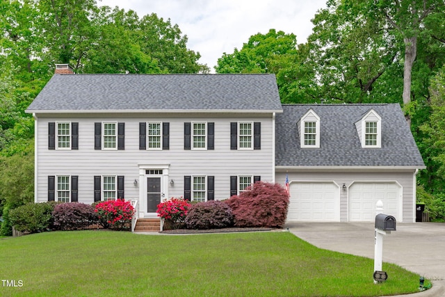 colonial house with concrete driveway, a front lawn, a shingled roof, a chimney, and a garage