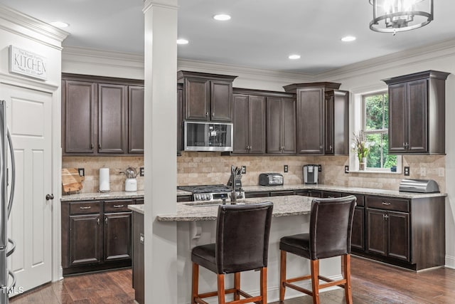 3304 Rockland Ridge Dr, Cary, NC 27519 - kitchen with stainless steel microwave, decorative columns, dark brown cabinets, dark wood-style flooring, and ornamental molding