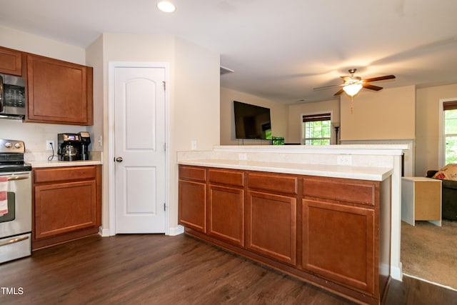 kitchen with appliances with stainless steel finishes, light countertops, brown cabinetry, a peninsula, and open floor plan