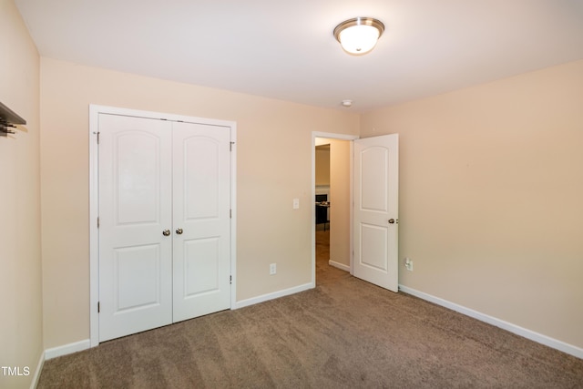 unfurnished bedroom with baseboards, carpet, and a closet