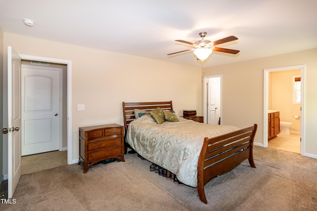 bedroom with baseboards, ceiling fan, light carpet, and ensuite bath