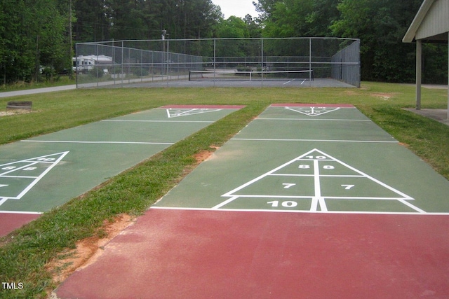 surrounding community with fence, a lawn, and shuffleboard