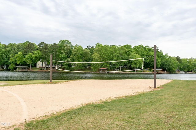 view of home's community with a lawn, a view of trees, a water view, and volleyball court
