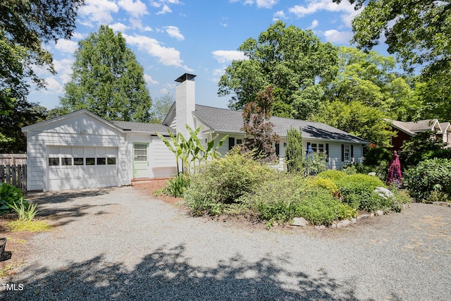 ranch-style house featuring a garage, fence, gravel driveway, roof with shingles, and a chimney