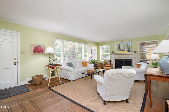 living area with crown molding, visible vents, wood finished floors, a fireplace, and baseboards