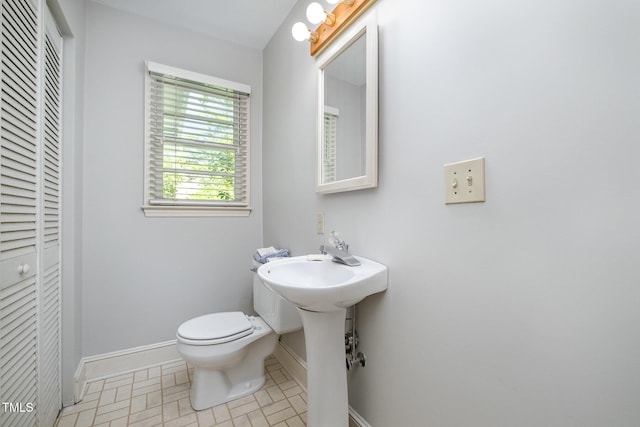 half bath featuring toilet, baseboards, and a closet