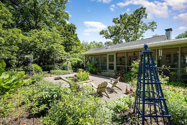 rear view of property featuring a chimney and a sunroom